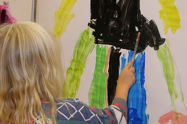 Kind malt mit Wasserfarbe an Leinwand