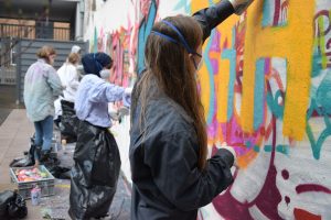 Bild: Die teilnehmerinnen des Graffiti Workshops besprayen eine Wand mit bunten Schriftzügen
