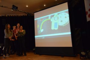 Bild: die Gruppe zeigtden Film, Auf der Leinwand sehen wir ein universum aus Papier und zwei Schweinchen, die über einen Regenbogen zu einem Einhorn in die Rakete steigen.