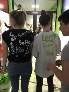 Bild: Viele menschen am streichen und zwei Mädchen in Malderkleidung, auf deren Rücken schon viele unterschriften gesammelt wurden