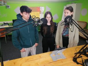 Drei Schüler*innen stehen zur Aufnahme vor den Mikrophonen bereit. 