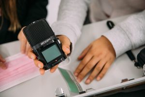 Zwei Teilnehmende halten ein Aufnahmegerät in die Kamera