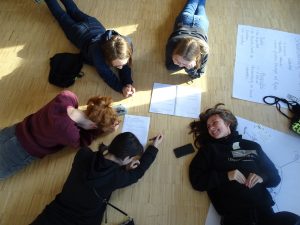 Jugendliche auf dem Boden beim Planen ihres Projekts und haben dabei Spaß