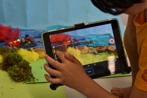 Tablet und gebastelte Meereslandschaft im Hintergrund und auf dem Bildschirm