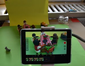 Tablet das Playmobilfiguren filmt, die an einem Tisch sitzen