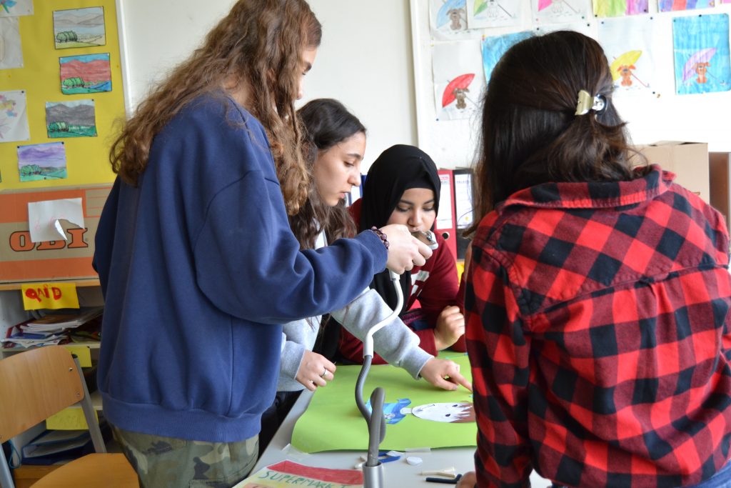 Auf dem Foto sind vier Mädchen zu sehen, die um einen Tisch stehen und an einem Trickfilm arbeiten.