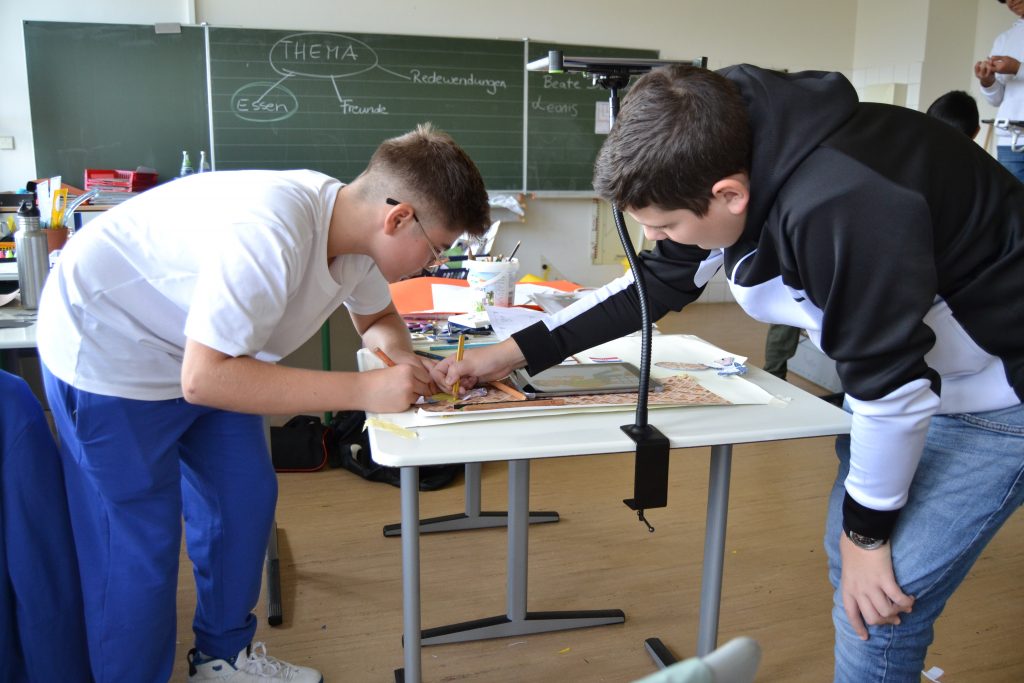 Auf dem Foto sind zwei Jungs in einem Klassenzimmer zu sehen, die auf einem Tisch gemeinsam an einem Trickfilm arbeiten.