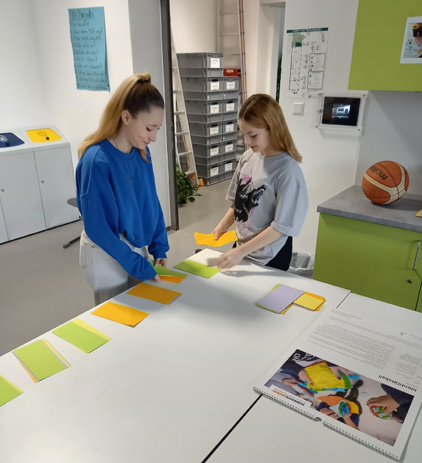 Zwei Mädchen stehen an einem Tisch und sortieren Karten