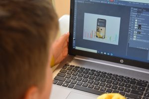 Jugendlicher sitz an Laptop und bearbeitet ein Bild