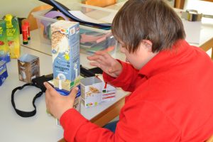 Ein Schüler bastelt mit alten Getränkekartons.