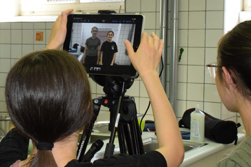 Zwei Schülerinnen arbeiten mit einem Tablet auf einem Stativ.