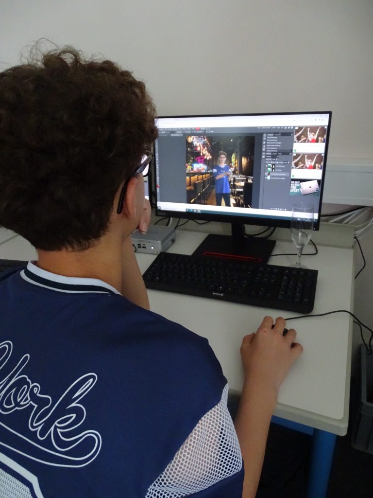 Junge sitzt am PC und bearbeitet ein Bild von sich selbst