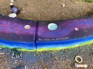 Ein teil der besprühten Bank im bunten Weltraum-Stil.