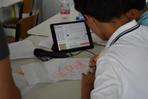 Junge schaut auf ipad. Auf Zettel vor ihm steht Gefahr