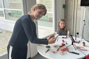 Ein Mädchen filmt mit einem ipad, ein weiteres Mädchen sitz an einem Tisch