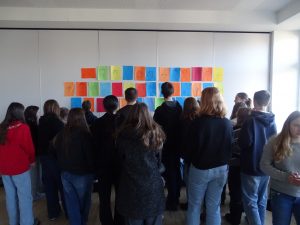 Die Teilnehmenden bestaunen die Portraits der Gruppe an der Wand