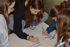 Vier Mädchen schreiben auf ein Plakat