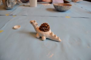 Ein Modellierter Dinosaurier mit einem Tannenzapfen auf dem Rücken