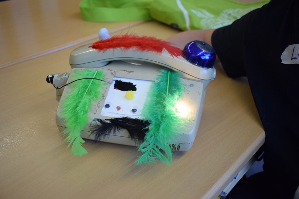 Kunstobjekt: ein altes Telefon, dekoriert mit Federn und einem eingebauten Licht.