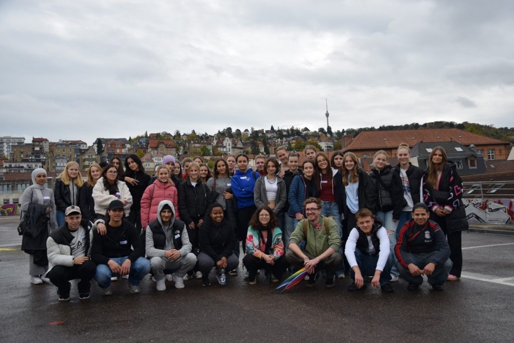 Gruppenfoto im Freien mit ca 30 der Teilnehmenden und dem Team. Im Hintergrund ist der Stuttgarter Fernsehturm zu sehen. 