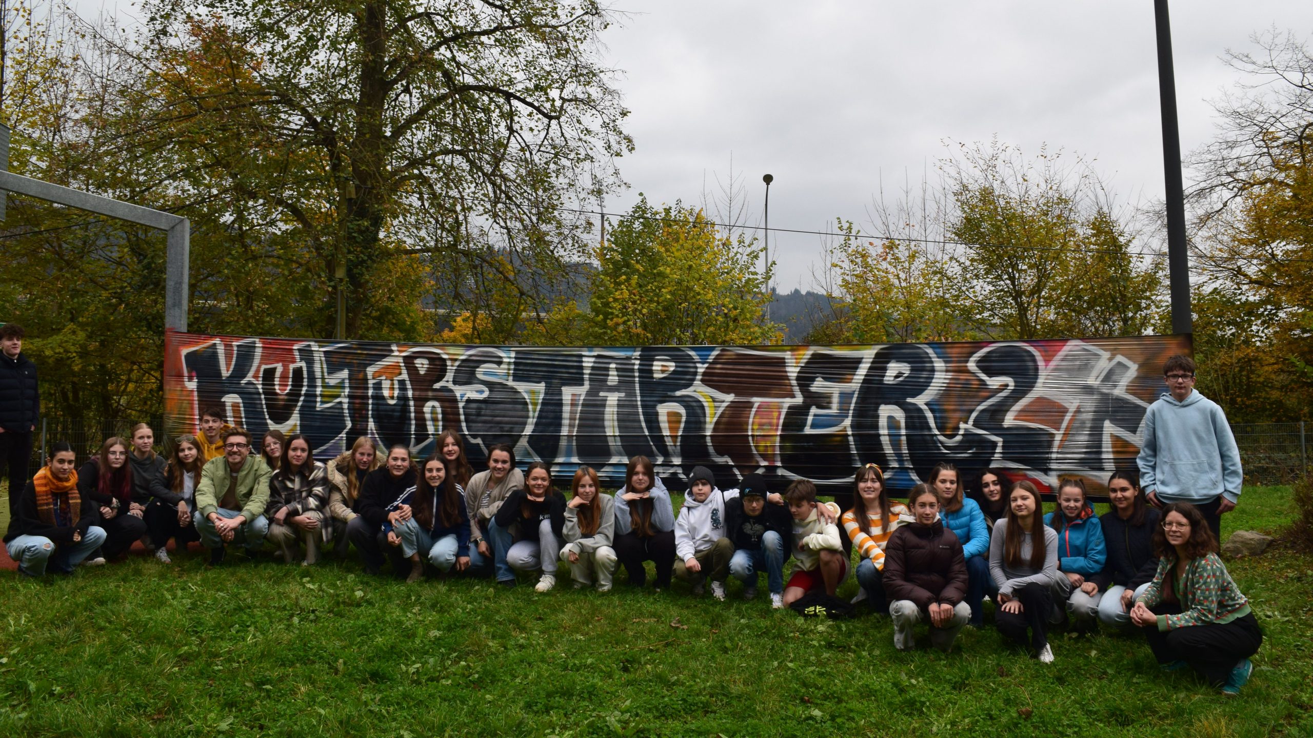 Gruppenfoto vor einem großen gesprühten Schriftzug "KulturStarter 24"
