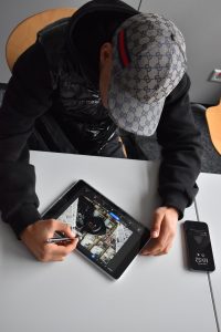 Junge mit Cap bearbeitet ein Bild am Tablet