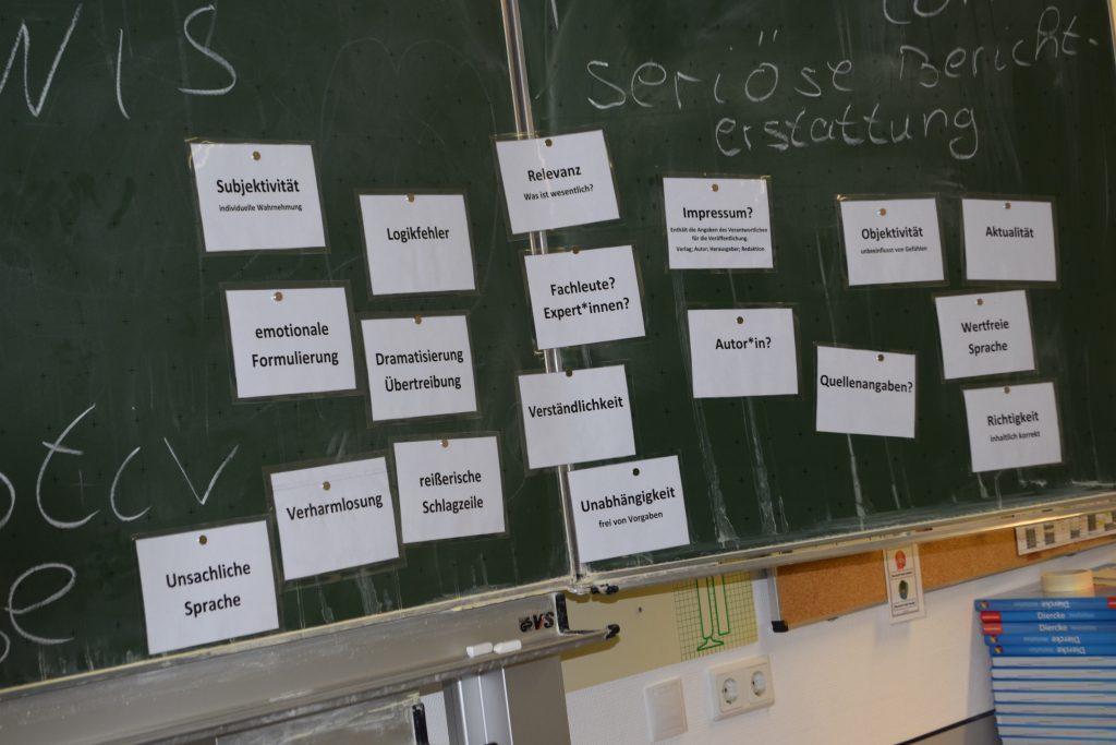 laminierte Karten sind mit Magneten an eine Schultafel gehängt. Auf den Karten stehen Kriterien für seriöse Berichterstattung, beispielsweise Subjektivität, unsachliche Sprache, Verharmlosung.