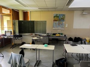 Blick in das Klassenzimmer. Offene Technikkoffer, eine Tabelle  it den Arbeitsschritten an der Tafel.