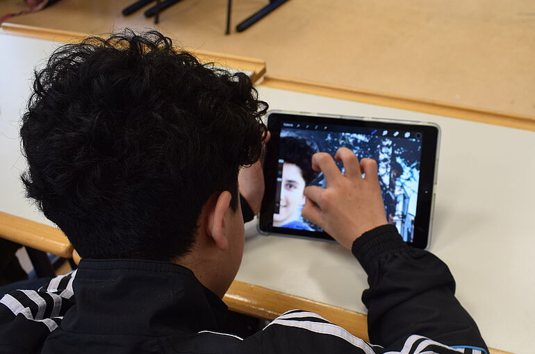 Zwie Jungs und ein Mädchen stehen hinter einer Kamera und nehmen ein Bild auf.