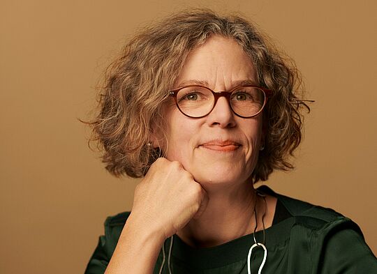 Eine Frau mit Brille lächelt in die Kamera (Portrait Foto)