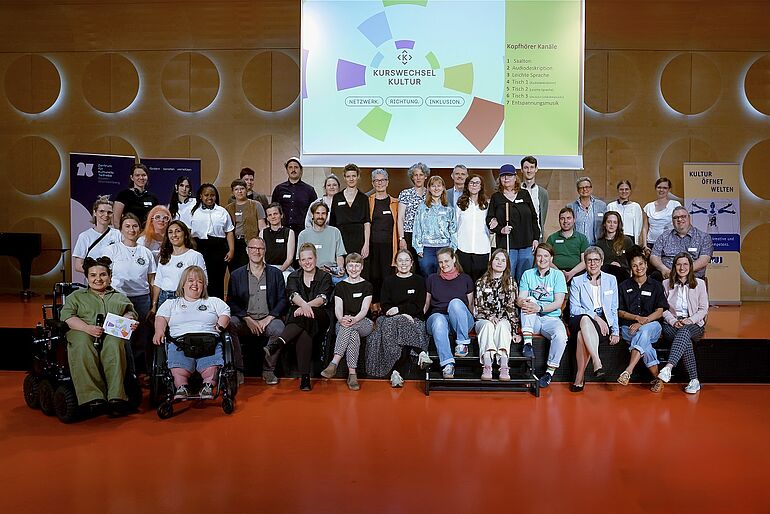 Gruppenbild mit Frauen und Männern, vorne links sitzen zwei Frauen im Rollstuhl 