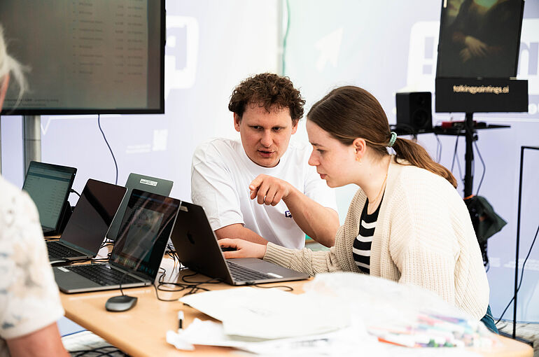 zwei junge Menschen sitzen vor einem Laptop 
