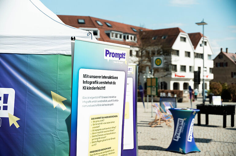 Zelt, Schautafel und Stehtisch auf einem Marktplatz zum Projekt Prompt - Dein Ki Event 