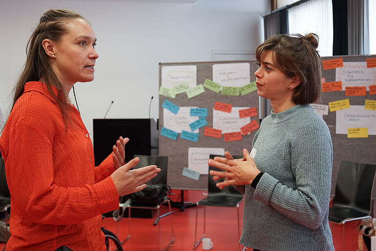 Zwei Frauen stehen sich gegenüber, und reden miteinander.