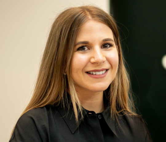 Eine Frau mit langen Haaren lächelt in die Kamera