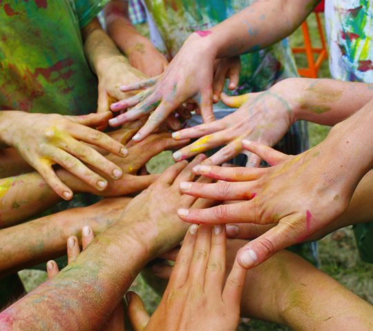 Viele Kinderhände liegen im Kreis übereinander 
